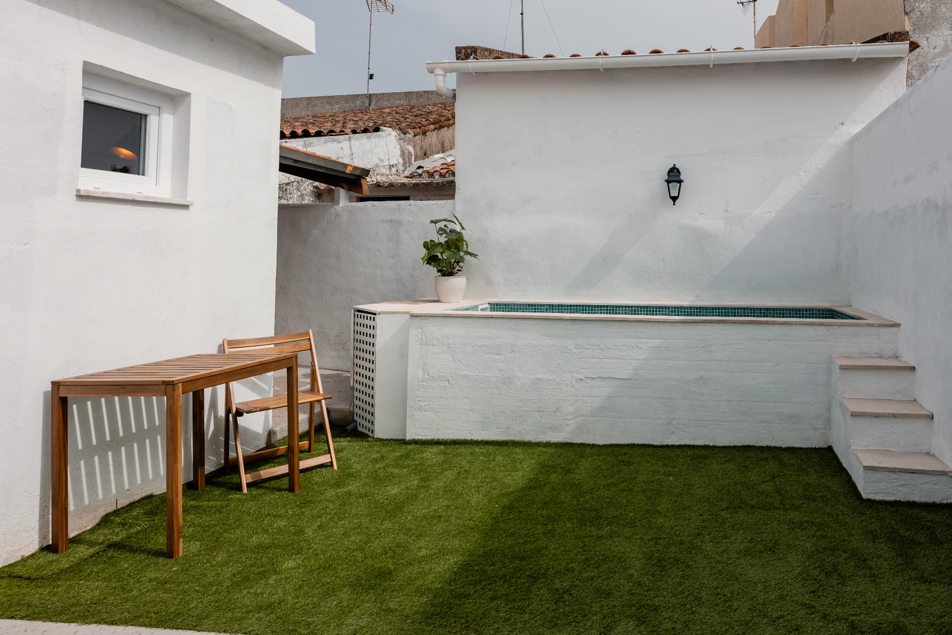 Pátio com relva artificial e mesa exterior